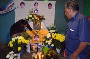 Ezequiel Mora, derecha, padre de Alexander Mora, uno de 43 estudiantes mexicanos desaparecidos desde septiembre observa mientras una persona no identificada toca una foto de su hijo en un altar en el pueblo de El Pericón. Foto: AP