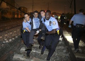 Personal de emergencia ayuda a un pasajero en el lugar de un accidente de tren, el martes 12 de mayo de 2015 en Filadelfia. Un tren de Amtrak con destino a Nueva York descarriló y se estrelló en Filadelfia.  (AP Foto/Joseph Kaczmarek)