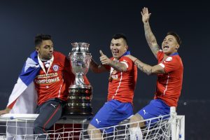 Chile's Gary Medel, center, and Chile's Eduardo Vargas, right, hold the trophy on top of the goal post after defeating Argentina in the Copa America final soccer match at the National Stadium in Santiago, Chile, Saturday, July 4, 2015. Chile became Copa America champions for the first time after defeating Argentina in a penalty shootout. (AP Photo/Ricardo Mazalan)