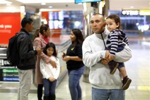 Gabriel Mejía sostiene a su hijo estadounidense Elías, de un año, mientras espera a otros dos hijos nacidos en El Salvador en el aeropuerto. Foto: AP