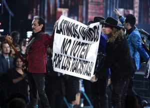 Los Tigres del Norte y Maná sostienen un letrero que dice “Latinos unidos no voten por los racistas” durante un número musical en la 16ª entrega de los Latin Grammy. Foto: AP