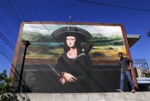 El muralista Levi Ponce posa frente a un mural que pintó en el barrio Pacoima de Los Angeles, en el que la Mona Lisa aparece con un sombrero de charro. Foto: AP