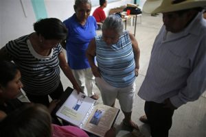 En esta imagen del 1 de diciembre de 2015, familiares de personas desaparecidas repasan un archivador lleno de imágenes e información sobre personas desaparecidas, en un sótano de la iglesia de San Gerardo en Iguala. Foto: AP