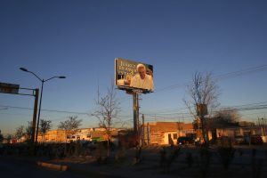 El sol de la tarde ilumina un cartel gigantesco con una imagen del papa Francisco y una leyenda que dice "Juárez es amor, estamos preparados". Foto: AP