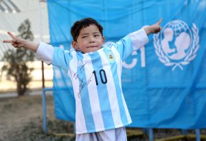 En esta foto suministrada por UNICEF, el niño afgano Murtaza Ahmadi posa con una camiseta de la selección de Argentina firmada por Lionel Messi el jueves, 25 de febrero de 2016, en Kabul, Afganistán.  (Mahdy Mehraeen/UNICEF via AP)