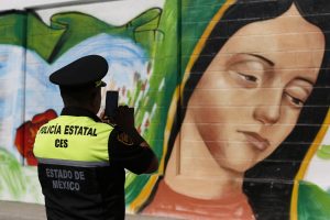Un policía toma una foto de un mural de la Virgen de Guadalupe en el barrio de Ecatepec de la Ciudad de México el 5 de febrero del 2016. El papa visitará la Basílica de la Virgen de Guadalupe durante su viaje a México. (AP Photo/Dario Lopez-Mills, File)
