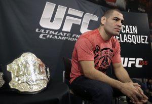 Sitting beside his championship belt, UFC heavyweight champion Cain Velasquez answers questions during a media availability Thursday, Oct. 17, 2013, in Houston. Velasquez will face former UFC heavyweight champion Junior Dos Santos in a rematch in Houston Saturday. He beat Santos in a five-round decision in December to regain the title after Santos won in a knockout in the first meeting in 2011. (AP Photo/Pat Sullivan)