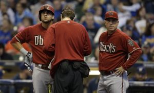 Arizona Diamondbacks' David Peralta, left, gets attention for an injury while batting as manager Chip Hale joins in during the first inning of a baseball game against the Milwaukee Brewers, Sunday, May 31, 2015, in Milwaukee. Peralta left the game.  (AP Photo/Jeffrey Phelps)