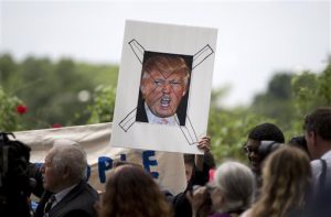 Manifestantes sostienen una fotografía tachada del magnate Donald Trump, aspirante a la candidatura republicana a la presidencia, durante una protesta contra él por haber dicho que los inmigrantes mexicanos eran delincuentes, cerca del nuevo hotel Trump, en Washington. Foto: AP