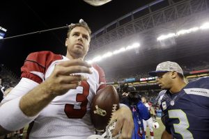Seattle Seahawks quarterback Russell Wilson, right, walks past as Arizona Cardinals quarterback Carson Palmer heads toward an interview after the Cardinals beat the Seahawks in an NFL football game, Sunday, Nov. 15, 2015, in Seattle. The Cardinals beat the Seahawks 39-32. (AP Photo/Elaine Thompson)