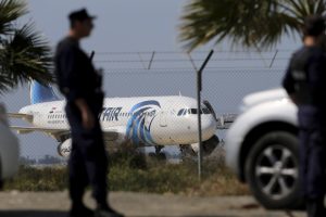 Agentes de policía hacen guardia junto a la valla de un aeropuerto con el avión secuestrado de EgyptAir en segundo plano, en el aeropuerto de Larnaca, en Chipre, el 29 de marzo de 2016. (Foto AP/Petros Karadjias)